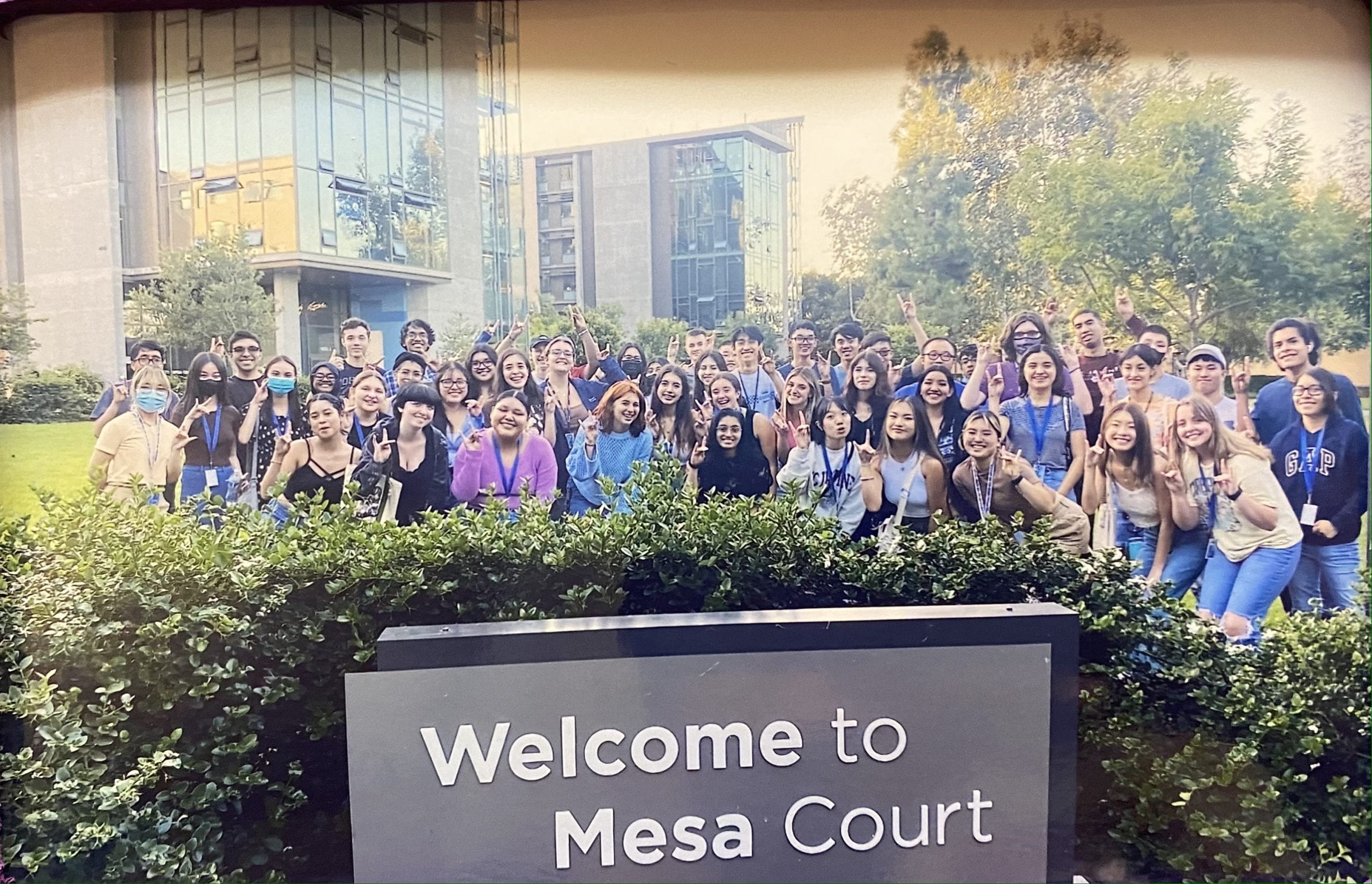 Large group of people posed behind a Mesa Court welcome sign